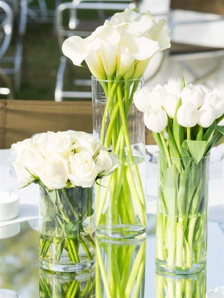 three vases filled with white flowers sitting on top of a table next to each other