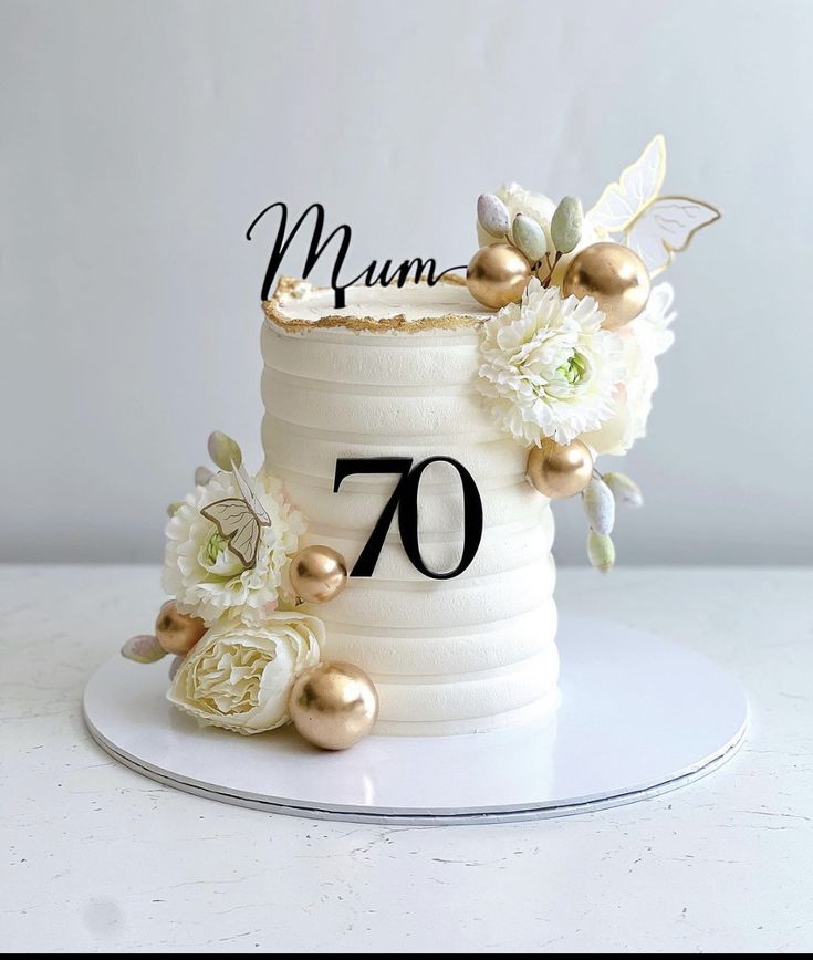 a white cake with gold decorations and the number seventy on it's top tier