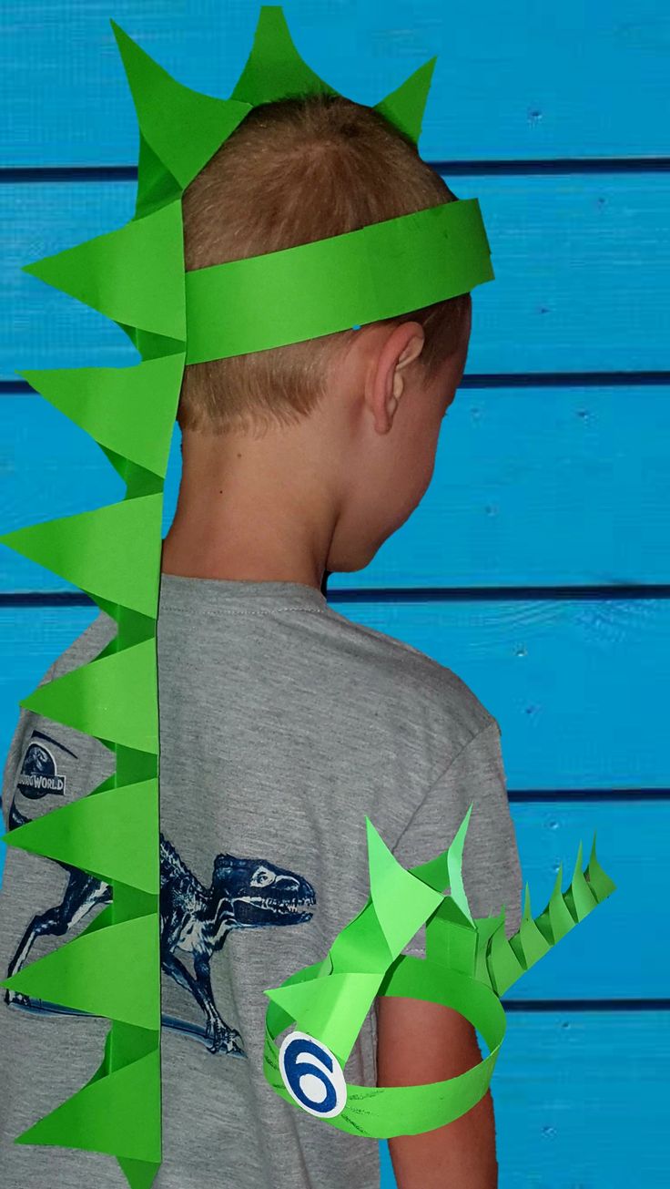 a young boy wearing a green paper crown and t - shirt with an alligator on it