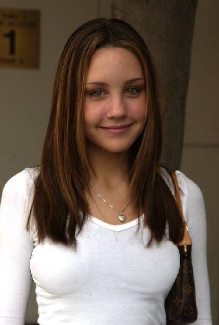 a woman with long brown hair wearing a white shirt and holding a brown leather purse