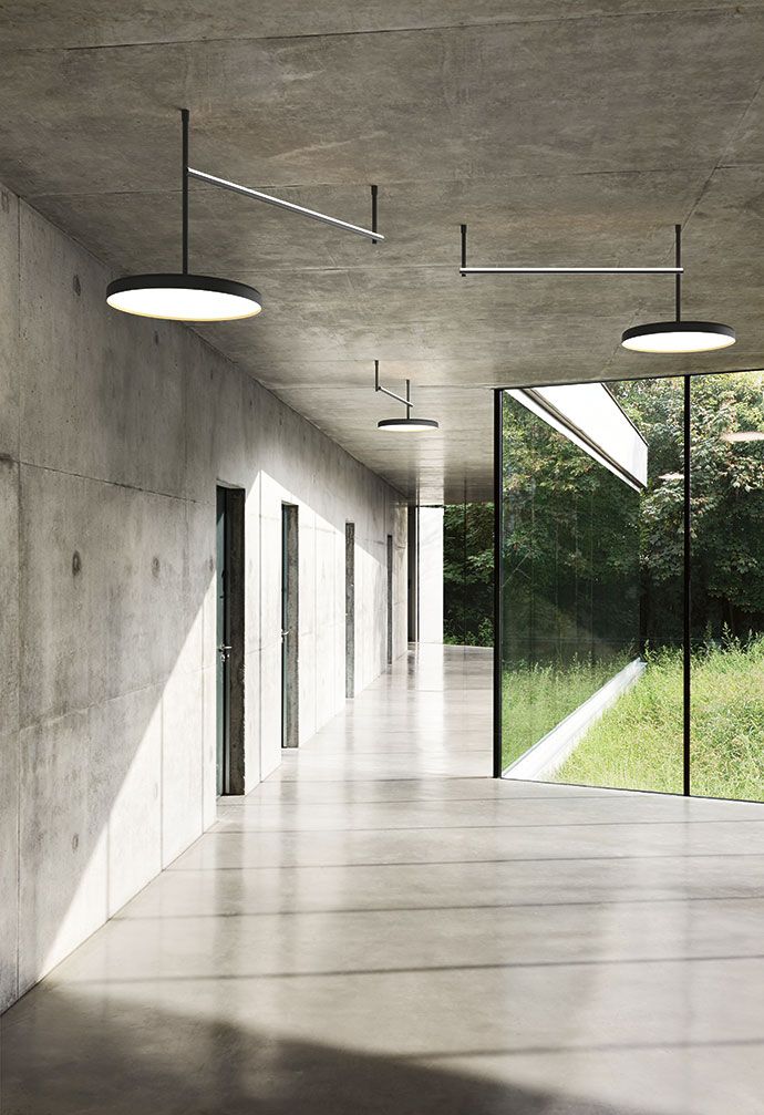 an empty hallway with glass walls and floor to ceiling windows that overlook the trees outside