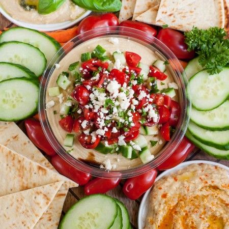 a platter filled with sliced cucumbers, tomatoes, and other veggies