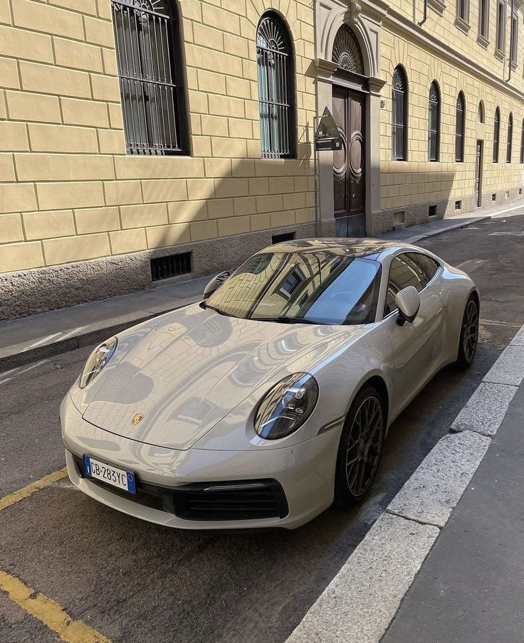 a white sports car is parked on the side of the road in front of a building