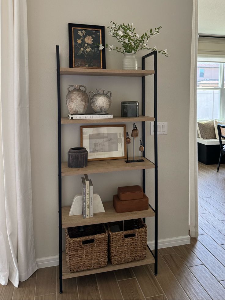 a bookshelf with baskets and pictures on it in the corner of a room