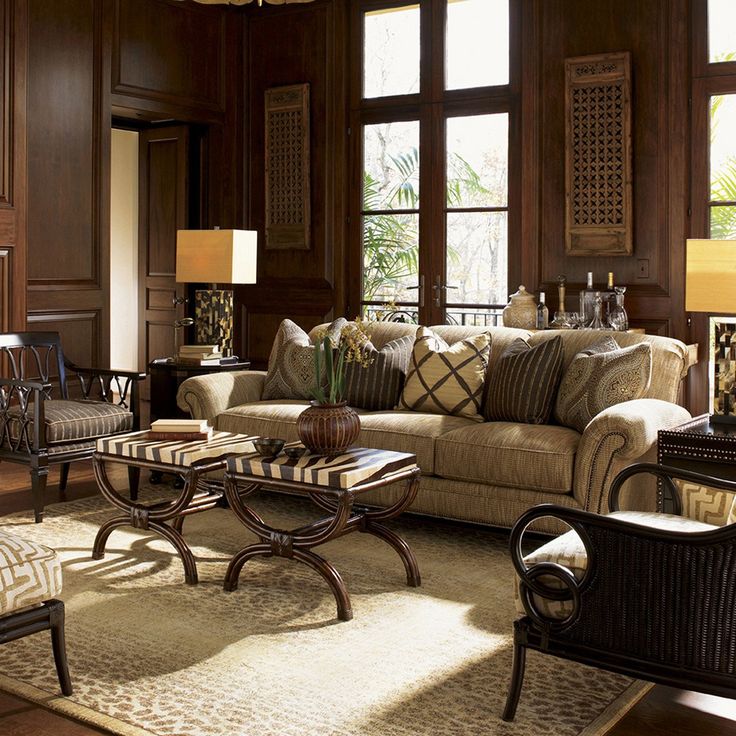 a living room filled with lots of furniture next to large windows and wooden paneled walls