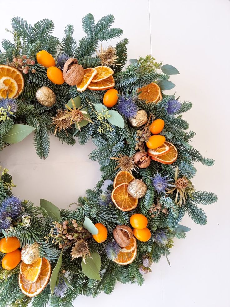 Seasonal winter wreath of Abies, eucalyptus, blue eryngium, dried orange slices, kumquat and walnut. Added a touch of gold. Wreaths With Oranges, Yellow Christmas Wreath, Blue And Orange Wreath, Navy And Orange Christmas Decor, Orange And Blue Christmas Decor, Blue Orange Christmas Tree, Christmas Wreath Blue, Blue And Orange Christmas Decor, Orange Slice Wreath