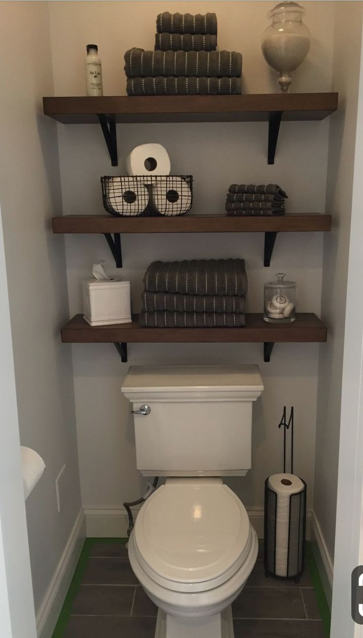 a toilet in a bathroom with shelves above it