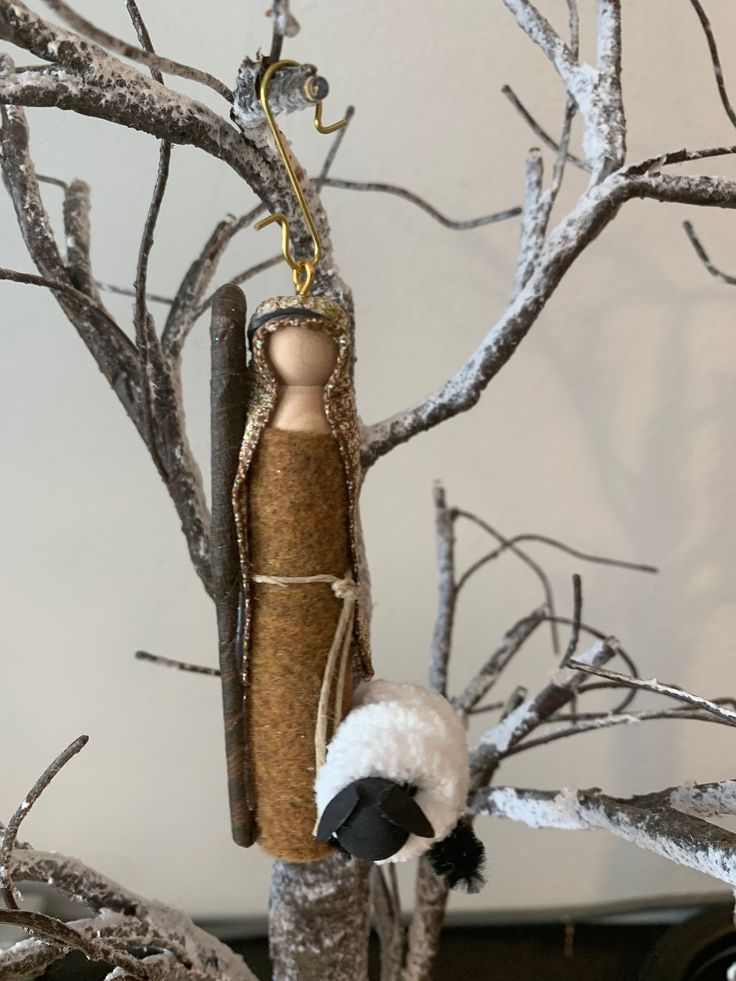 an ornament hanging from a tree with snow on the branches and a doll in it