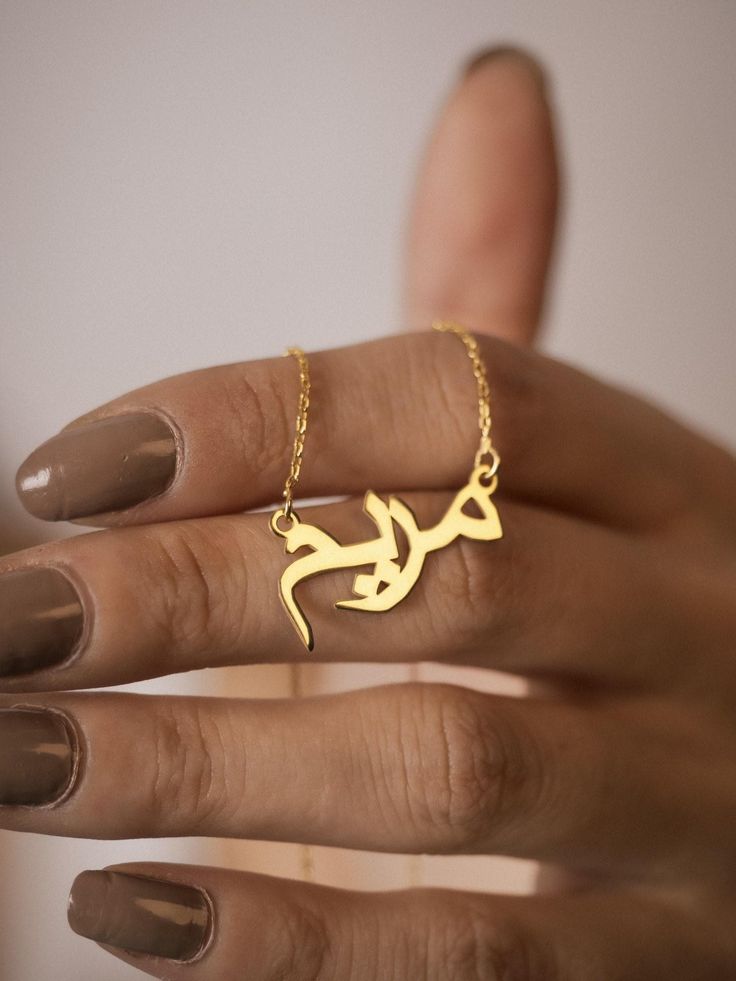 This personalized 14K gold Arabic name necklace promises to become a cherished symbol of your heritage and elegance. Imagine wearing this exquisite piece, a constant reminder of your unique identity. Crafted with meticulous attention to detail, this necklace will undoubtedly elevate your style, adding a touch of sophistication and modernity to any ensemble. The intricate calligraphy of your Arabic name will create a truly personalized and meaningful piece that will be admired for generations. Features and Benefits ✅ Personalized with your Arabic name ✅ Crafted from enduring 14K gold ✅ Authentic Arabic calligraphy design ✅ Adjustable chain for perfect fit ✅ Gift box included for luxurious presentation ✅ ✨-- M A T E R I A L S & F I N I S H --✨ ✅ Crafted from high-quality 925 sterling silver Personalized Gold Necklaces, Meaningful Gold Necklace For Personalized Gift, Meaningful Personalized Gold Necklace, Meaningful Gold Jewelry With Name, Meaningful Engraved Gold Necklace, Meaningful Personalized Gold Jewelry, Personalized Meaningful Gold Jewelry, Meaningful Engraved Yellow Gold Necklace, Gold Necklace With Name In Meaningful Style