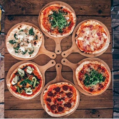 six pizzas on wooden platters sitting on top of a table