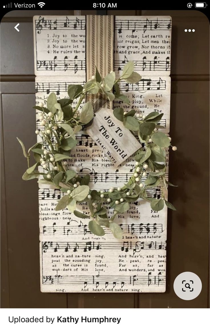 a wreath is hanging on a wall with sheet music notes and greenery around it