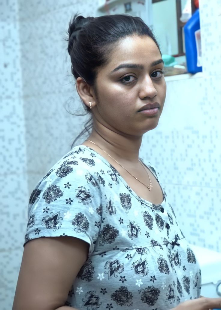 a woman standing in front of a sink holding a toothbrush and looking at the camera