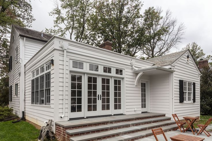 a white house with steps leading up to the front door and windows on each side