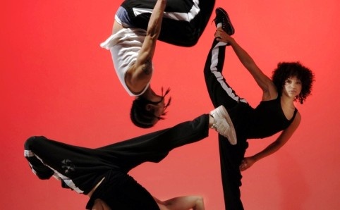 three people doing different poses in front of a red wall