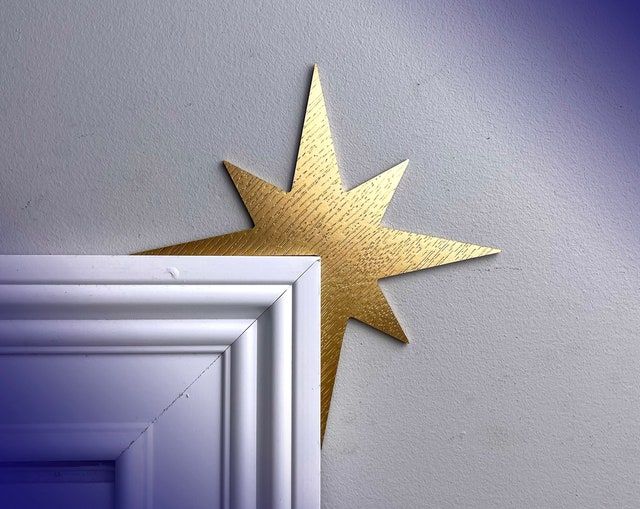 a gold star on the side of a white wall next to an open door with a blue background