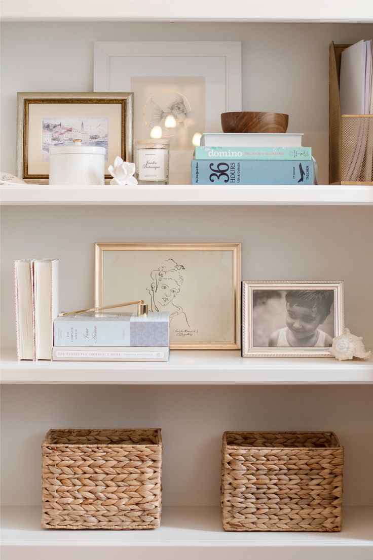 the shelves are filled with books, pictures and wicker baskets for storing things in