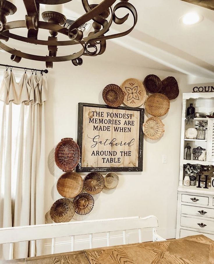 a wooden table sitting under a metal chandelier in a room with white walls