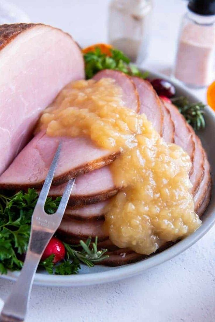 a plate with ham, mashed potatoes and gravy next to a knife and fork