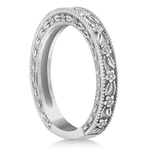 a wedding ring with intricate engraving on the sides and an oval design in white gold