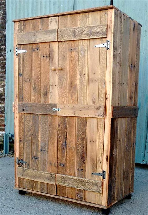 a large wooden cabinet sitting on top of a cement floor next to a building with metal studs