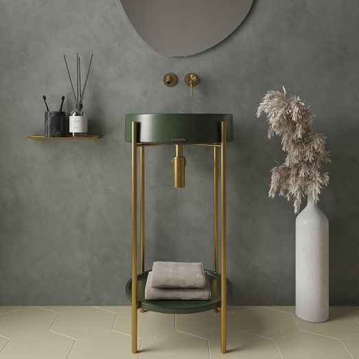 a bathroom with a round mirror above the sink next to a vase and towel rack