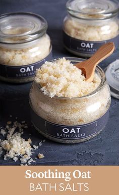 three jars filled with oatmeal sitting on top of a blue counter next to a wooden spoon