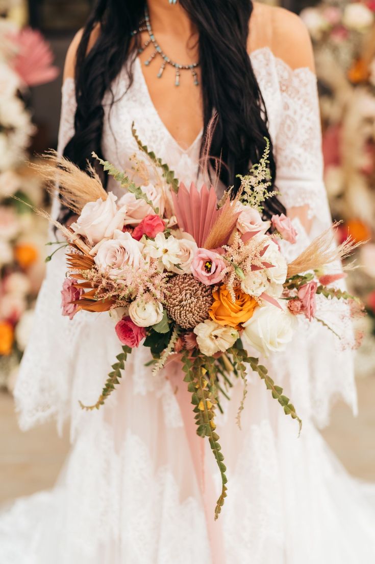 a woman holding a bouquet of flowers in front of her face and wearing a white dress