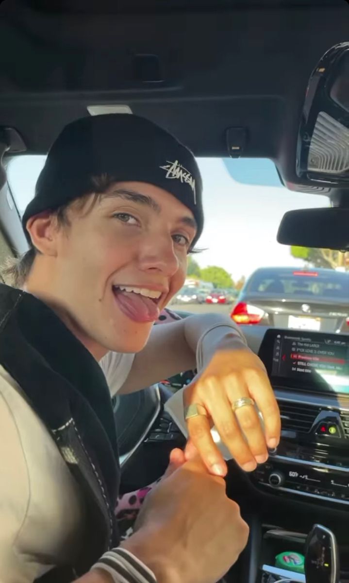 a young man is sitting in the driver's seat of a car and smiling