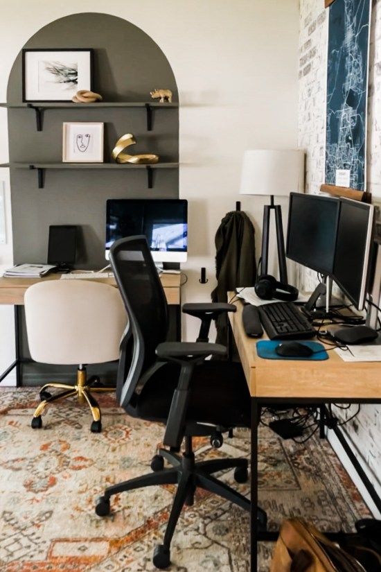 a home office with two computer screens on the desk and a rug in front of it