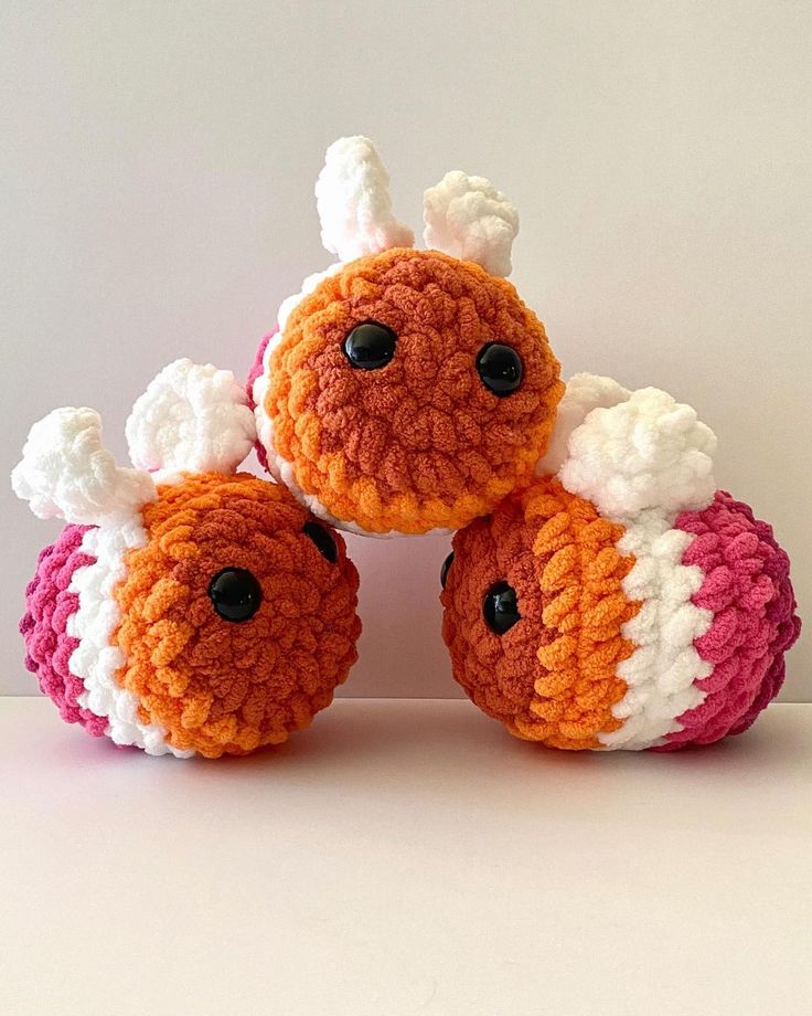 three crocheted stuffed animals sitting next to each other on a white table top