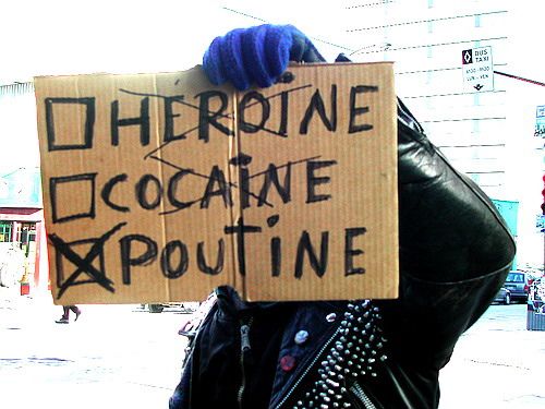 a person holding up a sign that says poutine addotion it may kill you, but would die with more money and a higher body weight