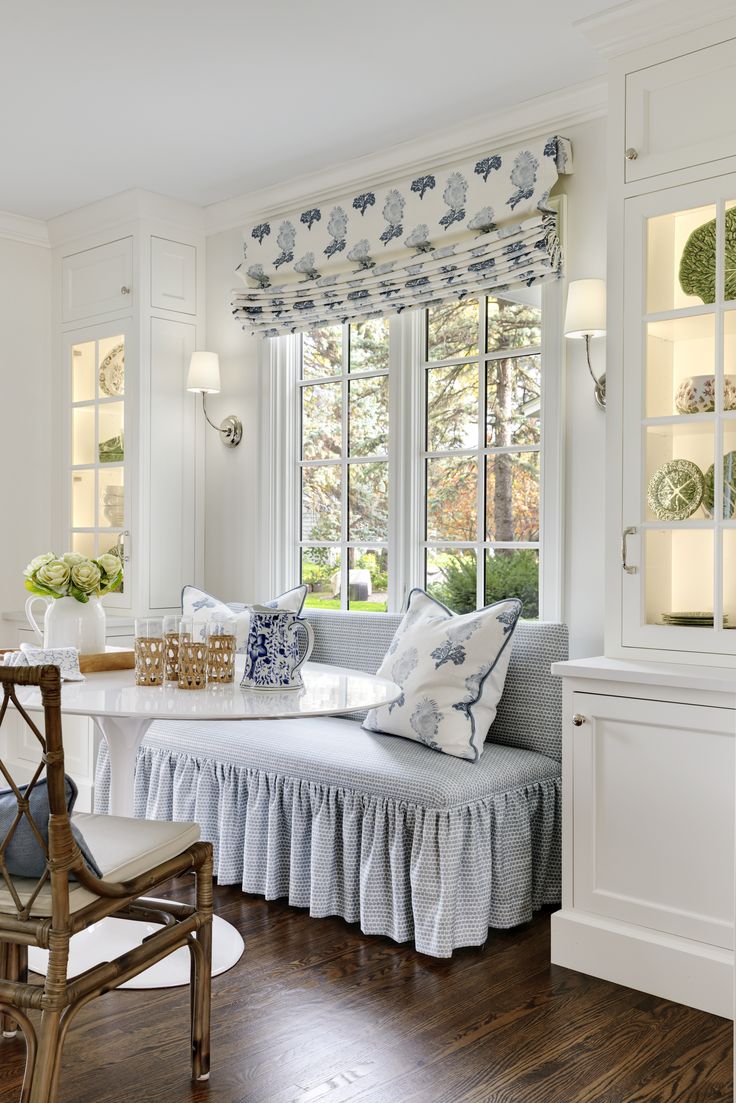 a living room filled with furniture next to a window covered in blue and white curtains