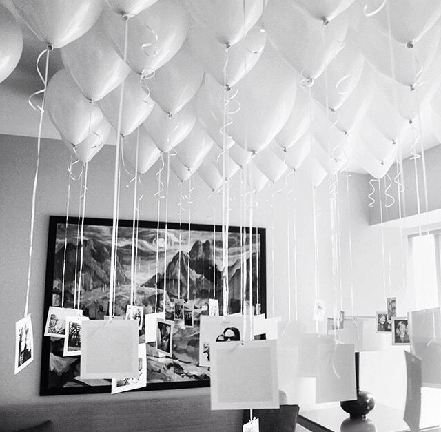 white balloons are suspended from the ceiling in a room with pictures and photographs on it