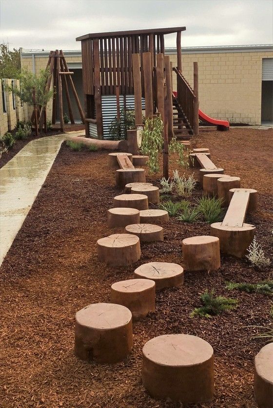 a wooden playground with benches and trees in the background