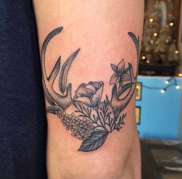 a deer's antlers with flowers and leaves on the side of his arm