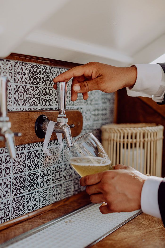 a person is filling a glass of beer from a faucet on the wall