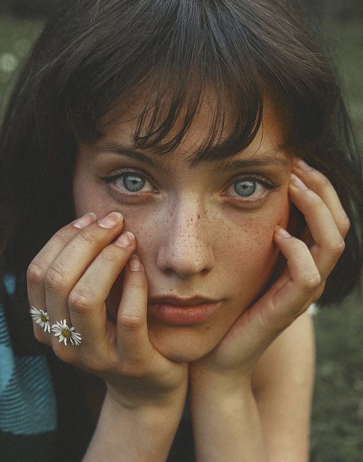 a young woman with freckled hair and blue eyes is posing for the camera