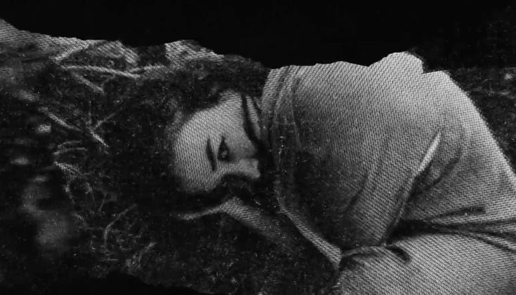 black and white photograph of a woman laying on the ground with her head in her hands