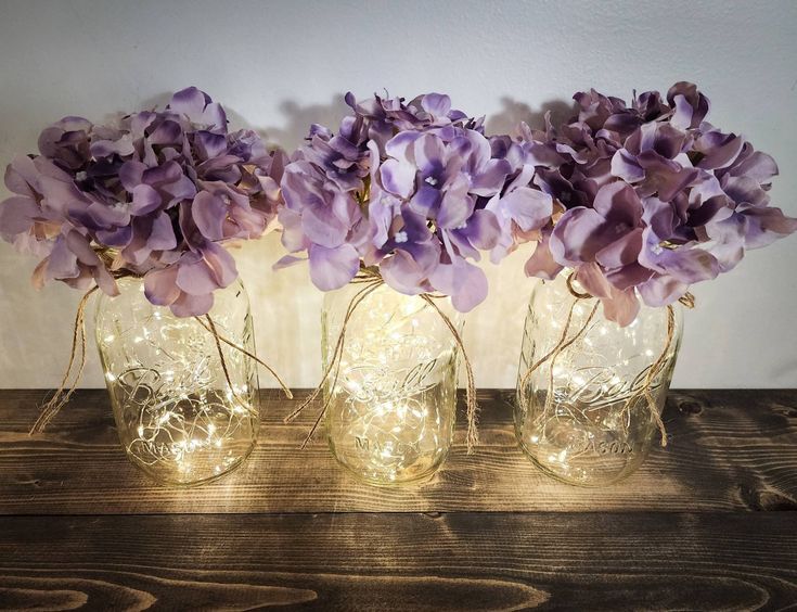 three glass vases with purple flowers in them