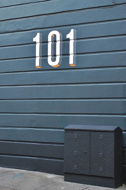 the number 101 is painted on the side of a building with two mailboxes