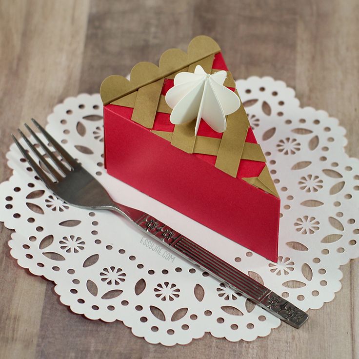 a piece of cake sitting on top of a doily next to a knife and fork