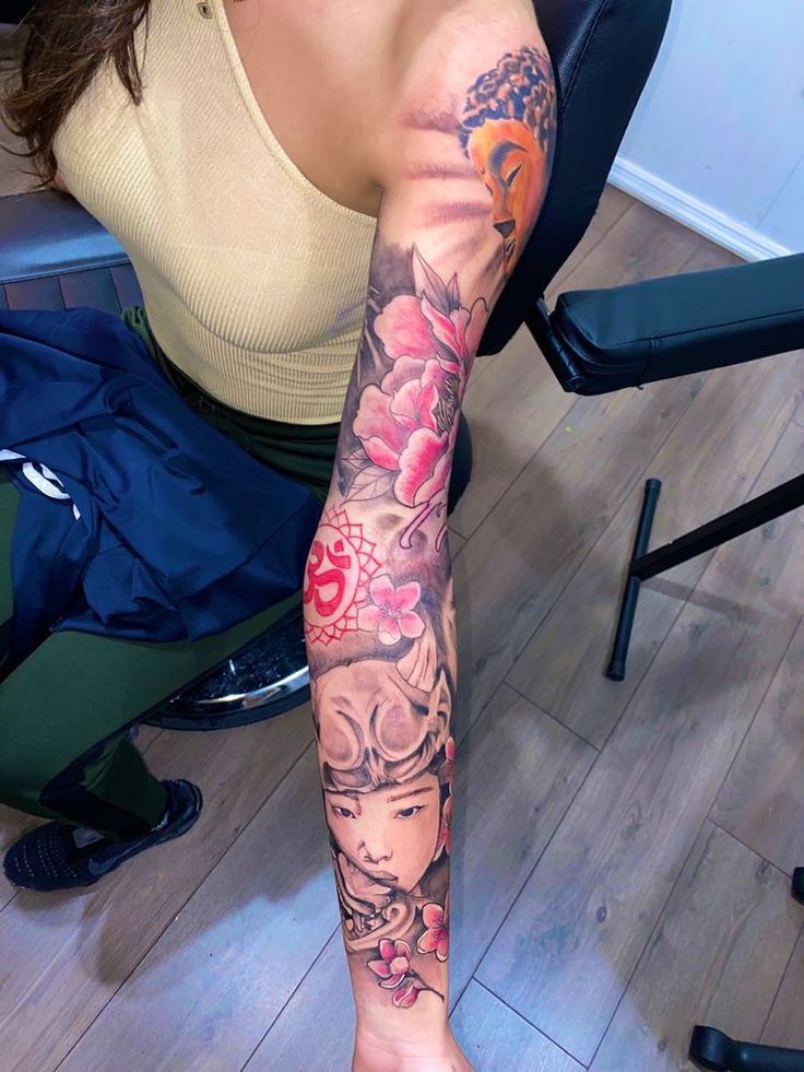 a woman is sitting on the floor with her arm covered in flowers and butterflies tattoo