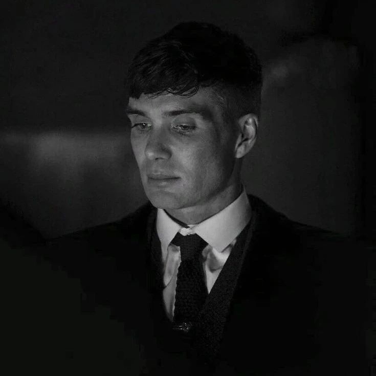 a man wearing a suit and tie in the dark