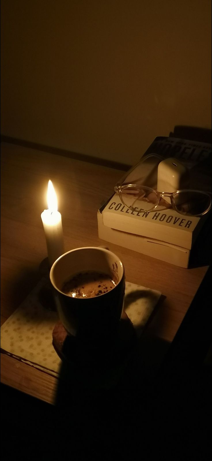 a cup of coffee sitting on top of a wooden table next to a lit candle