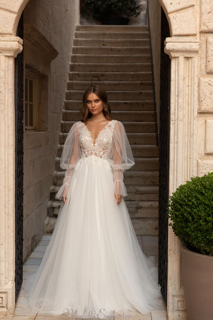 a woman in a wedding dress standing at the entrance to a building with stairs and potted plants