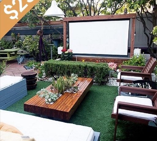 an outdoor movie is set up in the back yard with seating and tables for people to sit on