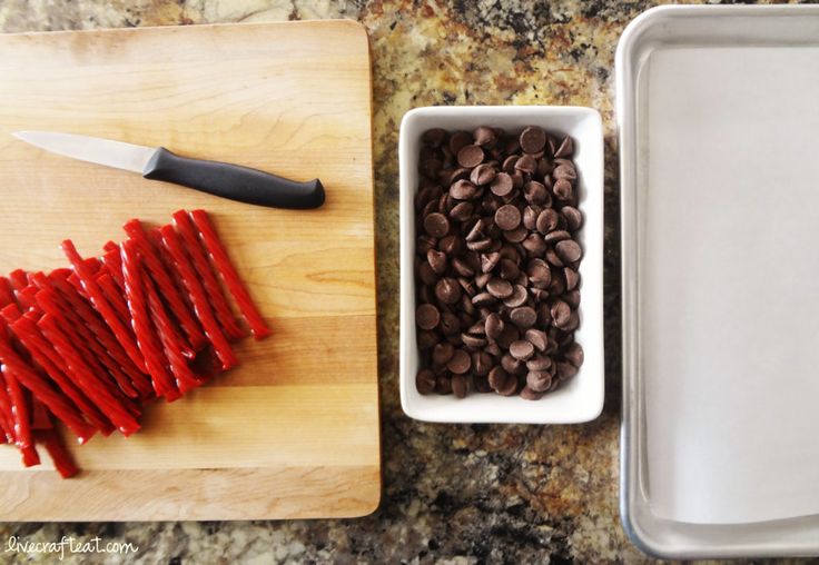 two trays with chocolate chips and a knife on a cutting board next to them