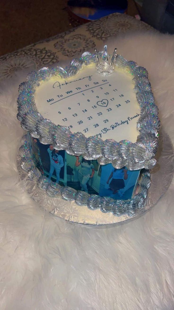 a blue and white birthday cake sitting on top of a fur covered table next to a clock