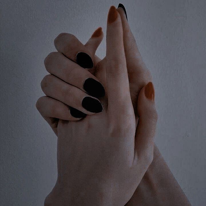 two hands with black and orange manicures holding each other's fingers in the air