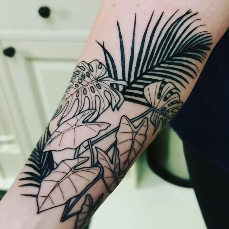 a black and white tattoo on the arm of a woman's arm with leaves